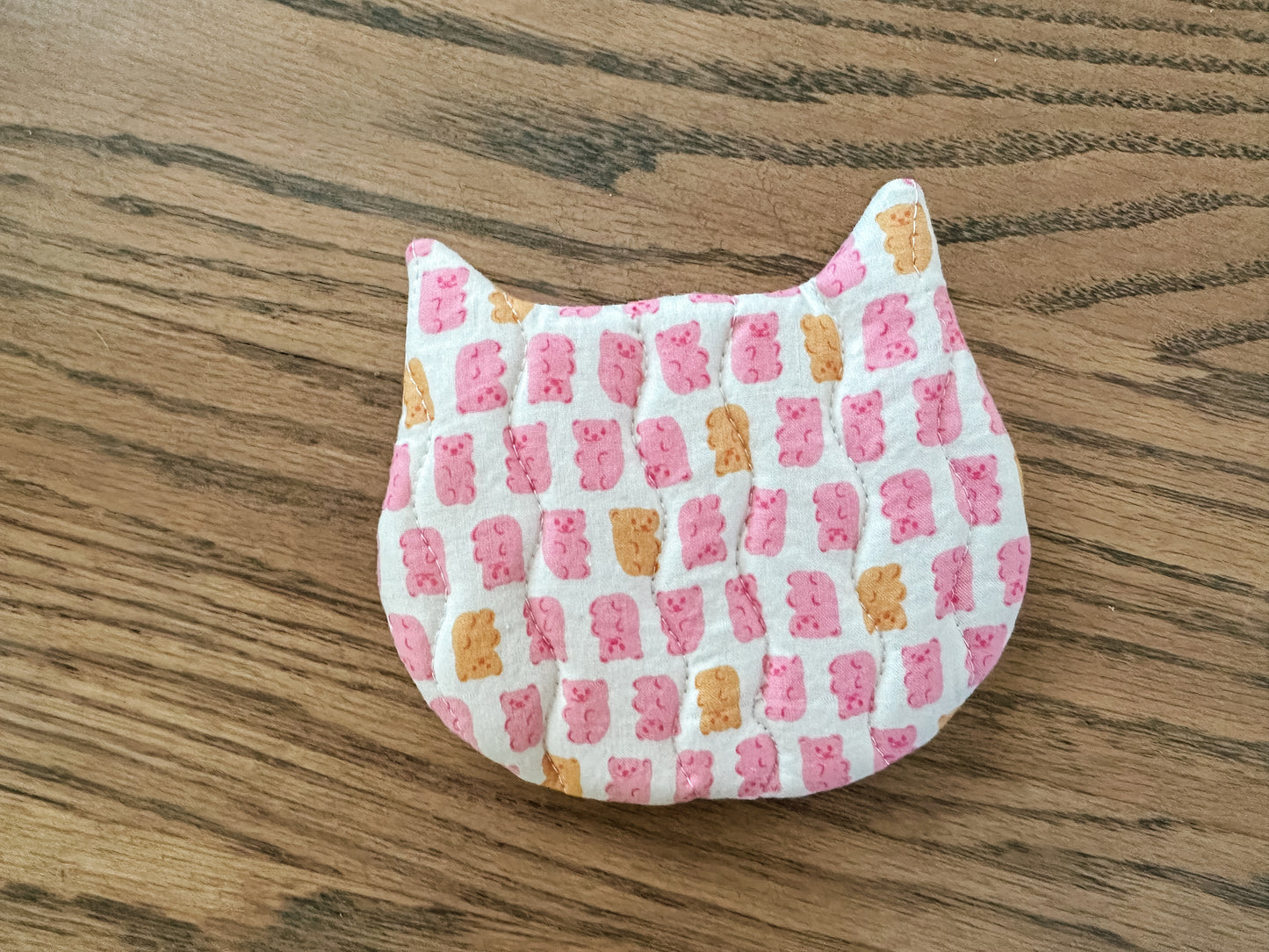 Fabric pouch with pink and orange checkered pattern on a wooden surface